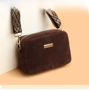 Detail of dark brown crossbody bag with retro woven strap and golden metal plate