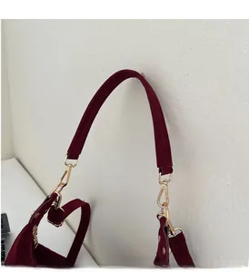 Detail of burgundy suede shoulder strap with polished gold-tone metal clasp hooks