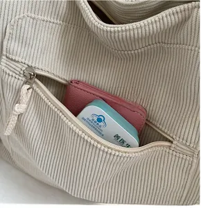 Detail of front zipper pocket on beige corduroy tote bag showing storage space