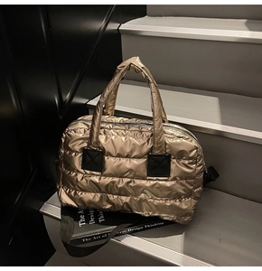 Close-up of champagne gold quilted tote bag on stairs with a design book as a prop