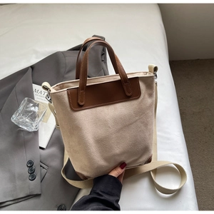 Detail of vintage beige tote bag showing leather handles and adjustable woven strap