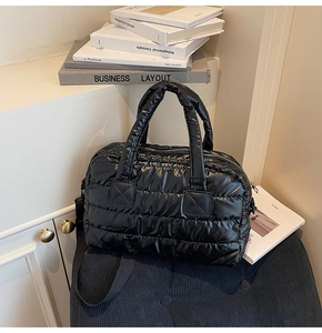 Detail of black quilted puffer gym bag with detachable strap in a modern setting