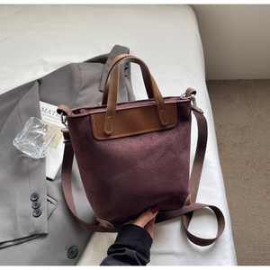 Close-up of retro suede tote bag with leather straps and reinforced corners in urban setting