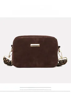 Front view of brown faux suede camera bag with golden plate and geometric strap