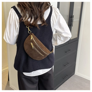 Detail of dark brown suede belt bag with gold zippers and adjustable wide strap