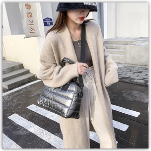 Close-up of a silver quilted puffer bag with glossy metallic finish and black strap