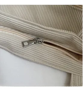 Close-up of a smooth silver metal zipper on a beige corduroy tote bag detail