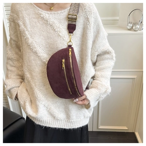 Detailed macro view of burgundy suede waist bag with wide geometric woven shoulder strap