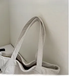 Close-up of beige corduroy tote bag with durable handles and brown lining detail