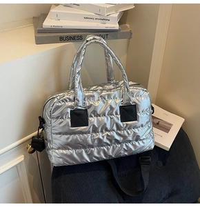 Détail du sac fourre-tout argenté matelassé avec poignées noires et texture brillante