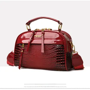 Détail du sac rouge en cuir verni gaufré croco avec logo FASHION en métal doré