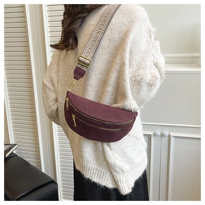 Detail of burgundy suede saddle bag with ethnic jacquard strap worn by a model