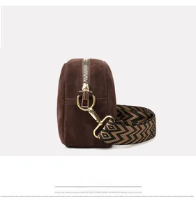 Detail view of brown matte leather shoulder bag with decorative woven strap and gold zipper