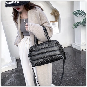Close-up of black quilted puffer tote bag with glossy finish and adjustable strap