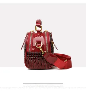 Détail d'un sac carré en cuir verni rouge avec motif crocodile et accents dorés