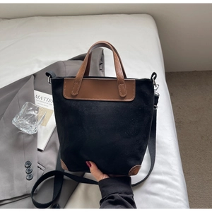 Dettaglio della borsa tote nera in finto camoscio con accenti in pelle marrone su letto
