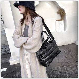 Macro detail of black quilted down tote bag with nylon texture and wide shoulder strap