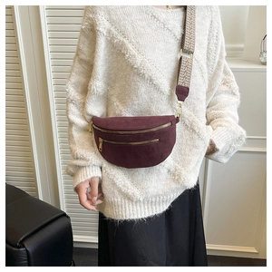 Detail of burgundy saddle bum bag featuring ethnic style wide strap and gold zippers