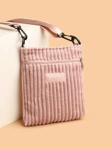 Detailed view of pink corduroy texture and embossed Perfect Lily brand label on crossbody bag