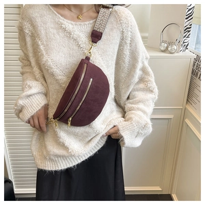 Detail of burgundy saddle bag with ethnic wide strap and vintage gold hardware