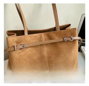 Gros plan sur un cabas en daim marron avec boucles argentées et finitions soignées