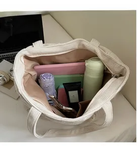 Detailed interior of a white corduroy tote bag showing spacious lining and zip pocket