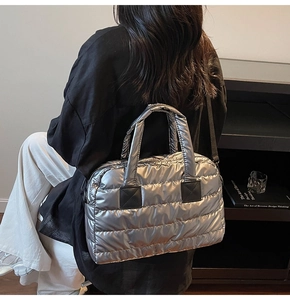 Close-up of metallic silver quilted fitness bag with black leather handle details