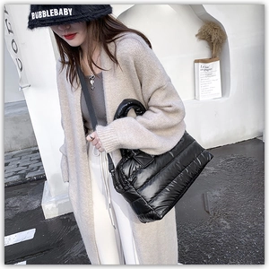Detail view of a black quilted puffer tote bag with a glossy finish and a nylon strap