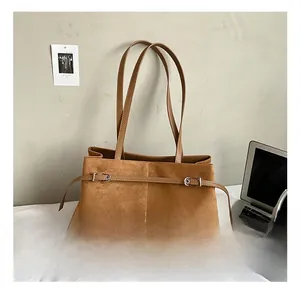 Détail du sac à épaule en daim marron avec boucle métallique et texture douce raffinée