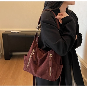 Detail of burgundy suede hobo bag with gold zippers and hardware on a shoulder strap