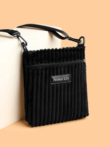 Detailed view of black corduroy crossbody bag with adjustable strap and brand tag