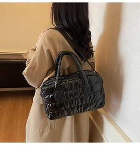 Side view of model wearing a black quilted puffer tote bag with glossy finish and wide strap