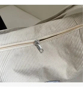 Detail des Metall-Reißverschlusses an einer beigen Cord-Umhängetasche aus Baumwolle