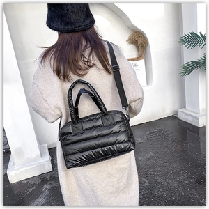 Detail of black quilted down tote bag featuring nylon texture and adjustable strap