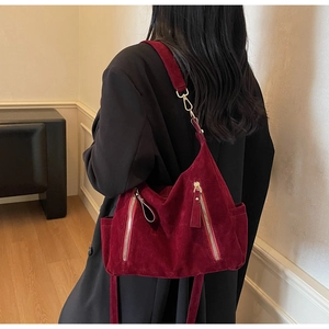 Burgundy suede tote bag with metal zipper and side pocket shown from a back view on a model