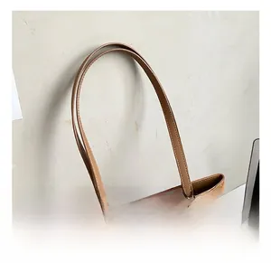 Détail du cabas en daim marron avec fines poignées arrondies et boucle métallique ajustable