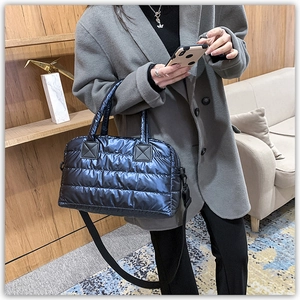 Detail of dark blue quilted down tote bag with nylon texture and adjustable strap