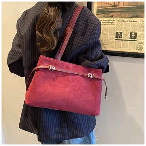 Détail d'un sac cabas en cuir givré bordeaux avec boucle en métal sur blazer marine