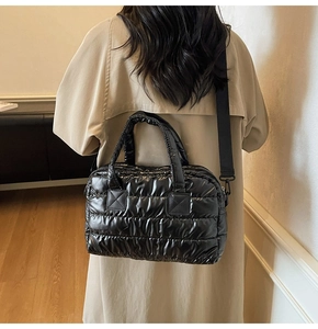 Quilted black puffer bag with adjustable wide shoulder strap shown on model's shoulder