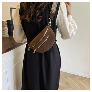 Detail of dark brown suede saddle bag with ethnic woven strap and golden zippers