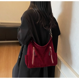 Detail of burgundy faux suede tote bag with side pockets and golden zip accents