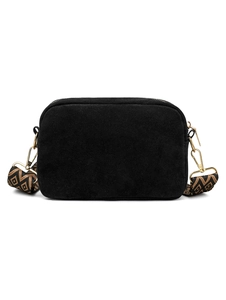Detail of black suede camera bag featuring a geometric woven strap and gold hardware