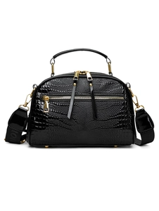 Détail du sac carré noir à texture crocodile avec finitions dorées et bandoulière