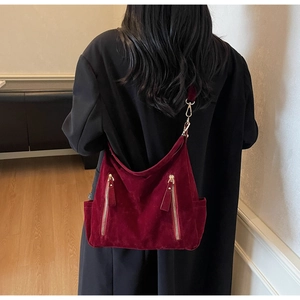 Detail view of burgundy velvet tote bag with gold metal hooks and side zippers