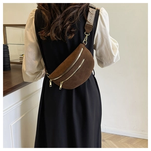 Detail of dark brown suede chest bag with gold zippers and woven geometric strap