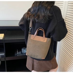 Dettaglio di una borsa a secchiello vintage in pelle scamosciata indossata da una modella