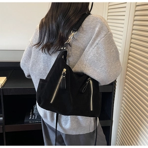 Detailed back view of a large black suede tote bag with dual gold zippers and adjustable strap