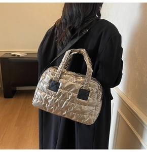 Gros plan d'un sac cabas matelassé doré avec bandoulière noire porté par un modèle