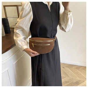 Close-up of brown suede fanny pack with dual golden zippers and adjustable strap
