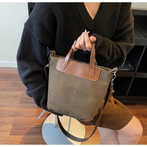 Dettaglio della borsa in tela verde oliva con accenti in pelle marrone in un interno autunnale